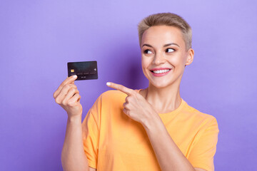 Fototapeta premium Portrait of charming cheerful girl toothy smile look direct finger arm hold debit card isolated on purple color background