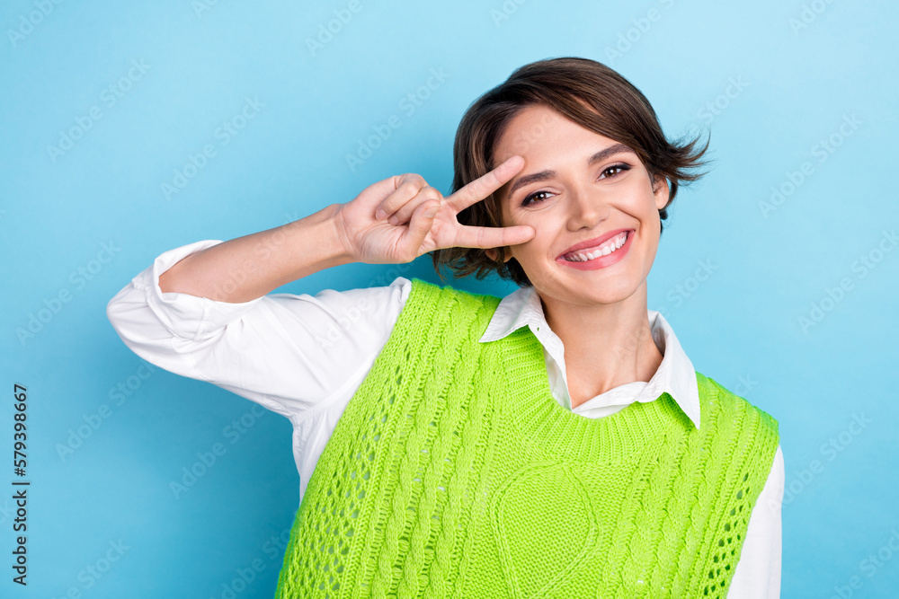 Sticker Photo of pretty positive lady beaming smile hand fingers demonstrate v-sign near eye isolated on blue color background