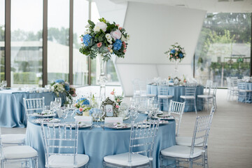 Served wedding table with decorative fresh pink, blue flowers and candles. Celebration details....