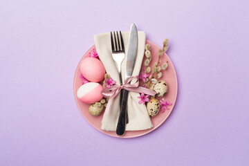 Easter table setting with spring flowers and cutlery on color background, top view