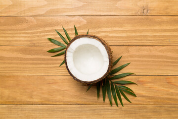 Fototapeta na wymiar Coconut with leaves on wooden background, top view
