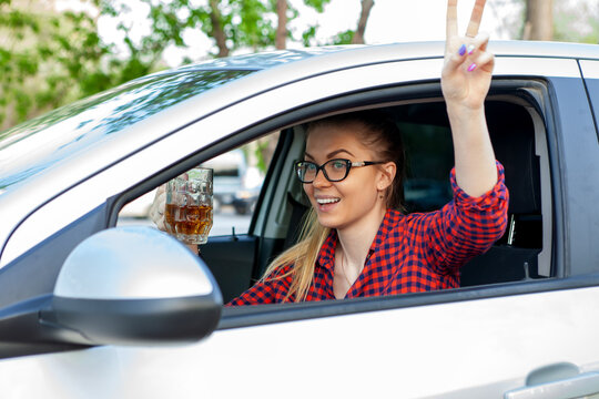 Drunk Driving. Drunk Woman Drives A Car. Woman Drinking Alcohol While Driving And Having Fun