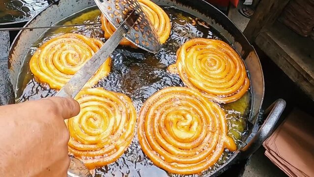 Indian traditional sweet food jilebi , made of gram flour sugar syrup frying in deep oil.Big jilabi making with smooth motion.