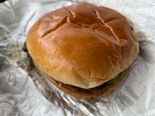 A homemade hamburger laying on a foil wrap