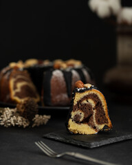 Dark chocolate bundt cake decorated with chocolate ganache glaze and nuts. Marble chocolate bundt cake. Zebra cake on a dark background.
