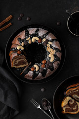 Dark chocolate bundt cake decorated with chocolate ganache glaze and nuts. Marble chocolate bundt cake. Zebra cake on a dark background. Top view