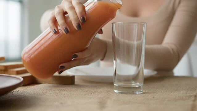 Close up unrecognizable woman pour orange juice from jar to glass on kitchen table. Female hands pouring fresh drink peach apricot smoothie healthy breakfast natural fruit vitamin keep diet healthcare