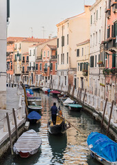 Fototapeta na wymiar Gondolier passing by on a canal in Venice, Italy