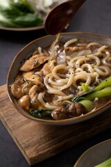 Asian-style udon noodles soup in a bowl on the table, vertical shot