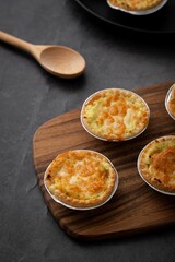 Vertical closeup of little pot pies served on a wooden tray