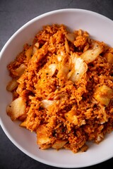 Vertical top view of a Korean kimchi in a white bowl on a gray table