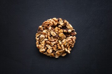 Top view of walnut seeds shaped as a circle on a black background
