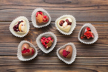 chocolate sweets in the form of a heart with fruits and nuts on a colored background. top view with space for text, holiday concept