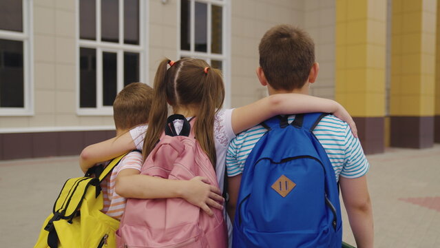 child schoolchildren with backpacks hug each other recess school yard. teamwork. school friends with school bags go lesson. happy childhood with friends. girl boy with a school backpack on his back.