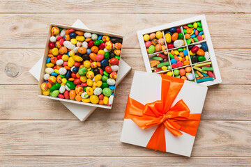 Set of different sweet candy in a paper box with a satin ribbon on a colored background. Holiday concept