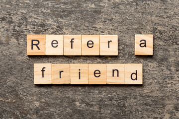 refer a friend word written on wood block. refer a friend text on table, concept - obrazy, fototapety, plakaty