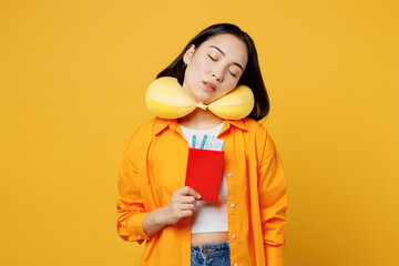 Young woman wearing summer casual clothes neck pillow hold passport ticket isolated on plain yellow background. Tourist travel abroad in free spare time rest getaway. Air flight trip journey concept.
