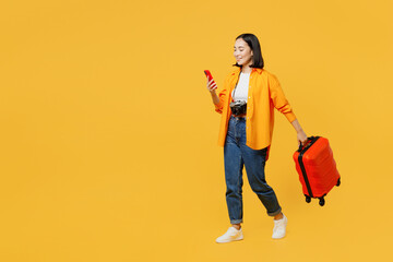 Sideways young woman wears summer casual clothes suitcase use mobile cell phone isolated on plain...