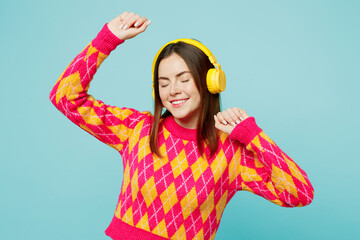 Young happy woman wear bright casual clothes headphones listen to music dance raise up hands...