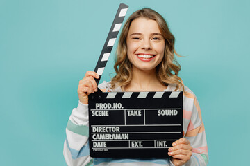 Young smiling happy cheerful blonde woman wear striped hoody hold in hand classic black film making clapperboard isolated on plain pastel light blue cyan background studio portrait. Lifestyle concept. - obrazy, fototapety, plakaty