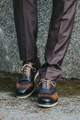 Vertical shot of a stylish man in gray suit pants and dark brogue shoes