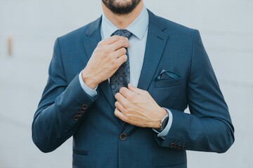 Man in a blue business suit fixing his blue tie