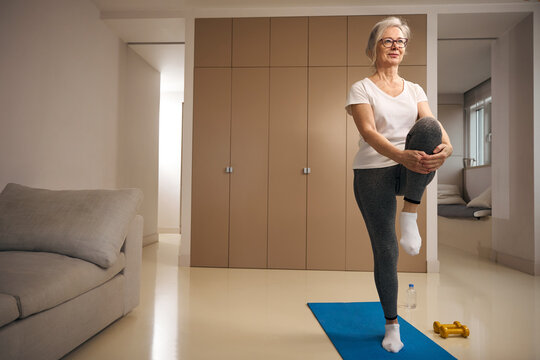 Elderly woman stands on one leg in a tree pose