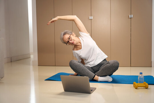 Older woman does an online workout in front of a laptop