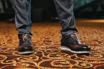 Stylish man in textured gray suit pants and brown and black brogue shoes
