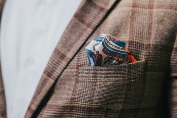 Closeup of a man's brown check suit jacket with a paisley pocket square