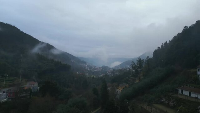 Aerial shot of Caldas de Gerez in a cloudy day full of fog surrounded by the valley, in Peneda Ger&ecirc;s, Portugal