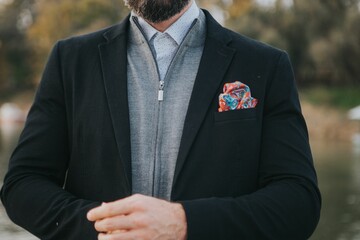 Man wearing a casual gray zipper jacket under a suit coat with bright, colorful pocket square © Omar Tursić/Wirestock Creators