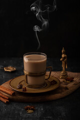 Indian masala chai with spices, brown sugar and cinnamon sticks. Hot masala tea in a glass with...