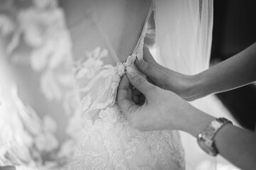 View of female hands helping bride to wear wedding dress
