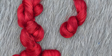 silk knitting yarn, a beautiful display, red silk thread wiht grey dusty background, AI Generated