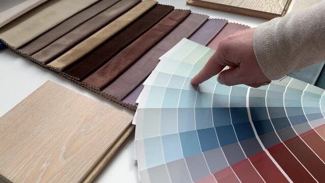 Top view: female interior designer chooses from color palette the best color for her client. Concept: the architect selects the color of textiles and wall paint. Paint color sample