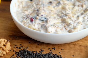 Homemade granola with yogurt for breakfast in a white bowl. Fresh banana, apple on wooden table. Health food concept.
