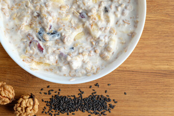 Homemade granola with yogurt for breakfast in a white bowl. Fresh banana, apple on wooden table. Health food concept.
