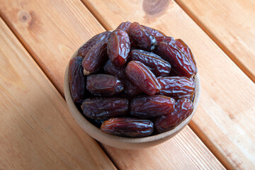 Date fruits in wooden bowl on wooden table,top view
