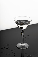 Splash from olive in a glass of martini. Black and white background. 
