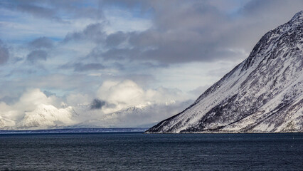 Snow covered Mountains surrounded by fjords in Norway during winter with icy mountain tops