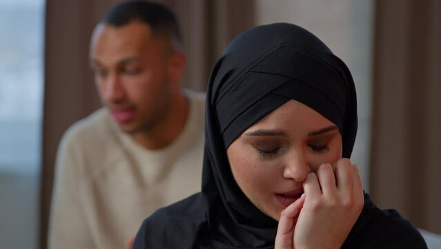 Couple quarrel sad hurt muslim woman in hijab crying feel desperate jealous husband angry man shouting accusing talking to wife. Breakup marriage divorce unwanted pregnancy family conflict home abuse
