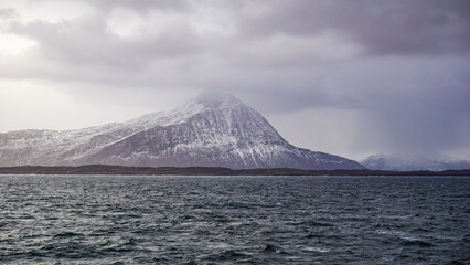 Snow covered Mountains surrounded by fjords in Norway during winter with icy mountain tops