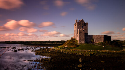 Old castle on a hill surrounded by a lake during a sunset at golden hour in Ireland