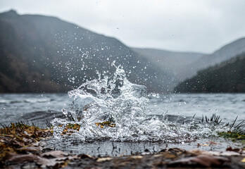Wave water splash on the shore of a lake in the mountains during a cold day in winter