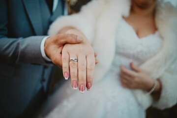 Groom holding the hand of his bride showing the wedding ring on her finger