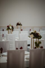 Vertical of the big tables decorated with flower bouquets prepared for the wedding ceremony