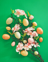 Romantic and beautiful Easter concept with painted eggs and almond blossoms. Green background. Flat lay.
