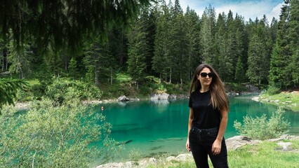 Fototapeta premium Caucasian girl wearing black outfit and standing by a lake in natural area in Davos, Switzerland