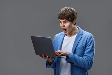caucasian young man using laptop isolated on gray background